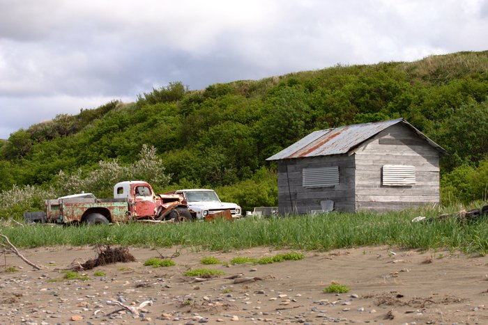 Rusting trucks and cabin along the beach.
