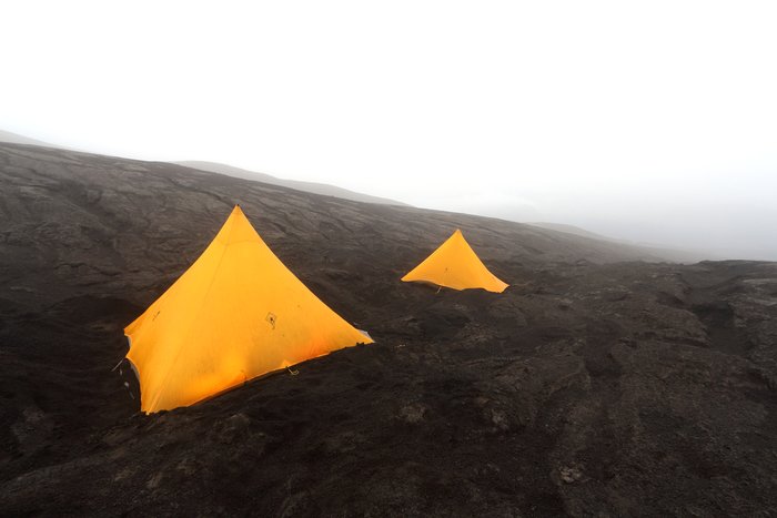 High on the flanks of Okmok Caldera, we set camp by first digging a flat spot out of thick cinders covering icy snow.