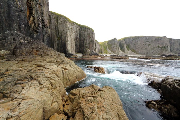 Swells surge across the rocks on a remote Aleutian coastline.