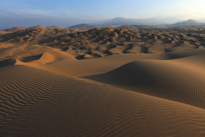 First sun illuminates an ocean of giant dunes in Peru.