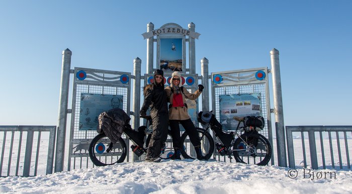 Kim and Bjørn pose for a photo under a sign in Kotzebue. After 36 days on the go they prepare to fly home. 