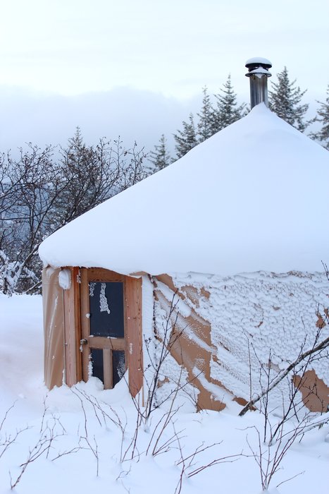 snow slowly accumulates on the roof of the guest yurt