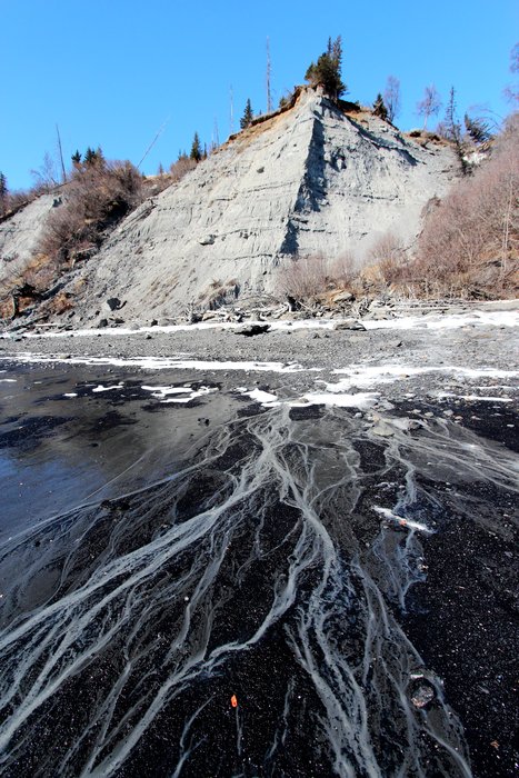 Rivulets of muddy water cross coal gravel near Homer, Alaska.