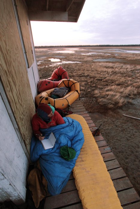 Erin writes in her journal from the porch of a duck shack on the Susitna Flats