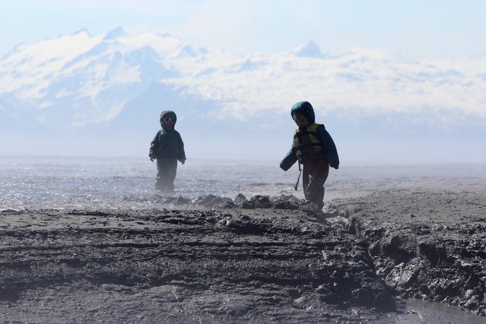 Kids play in the mudflats as they steam in the sun