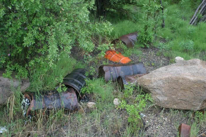 These drums are dumped off the highway into Alaska.  Some are out in the open, others are partially or completely buried and rusting away.