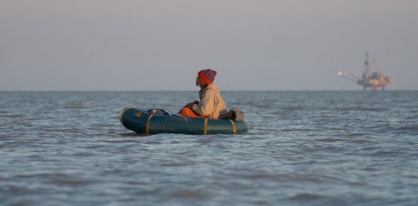 Packrafting in Cook Inlet with distant oil rig in background