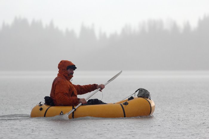 Carl Donnely paddles in the rain in a packraft.