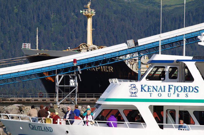 The Kenai Fjords tour boat cruises past the loading coal ship on its way into the harbor 