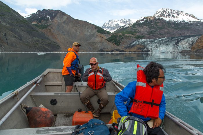 A three-person team takes a skiff ride near the landslide in upper Taan Fjord. A total of fourteen people, from various earth science backgrounds, joined the main summer expedition to study the landslide and tsunami, which occurred in October 2015. 