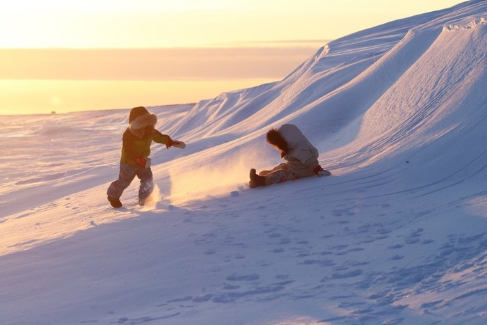 Kids playing on snowdrifts in the evening light