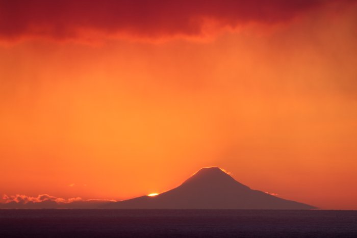 The vanishing sun illuminates wind-blown snow on Augustine Volcano.