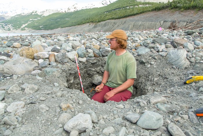 Dr. Bretwood Higman inspects deposit layers in a trench. Over the three-week 'main expedition', in June 2016, to study the landslide and tsunami, in Taan Fjord, Dr. Higman dug many trenches to better understand the landslide generated tsunami. 
