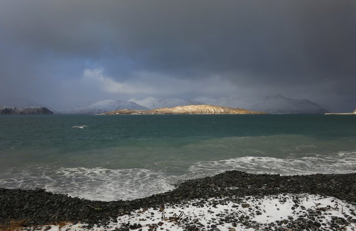 A spot of sun illuminates Hog Island as seen from the beach in front of the Fish and Game office in Dutch Harbor